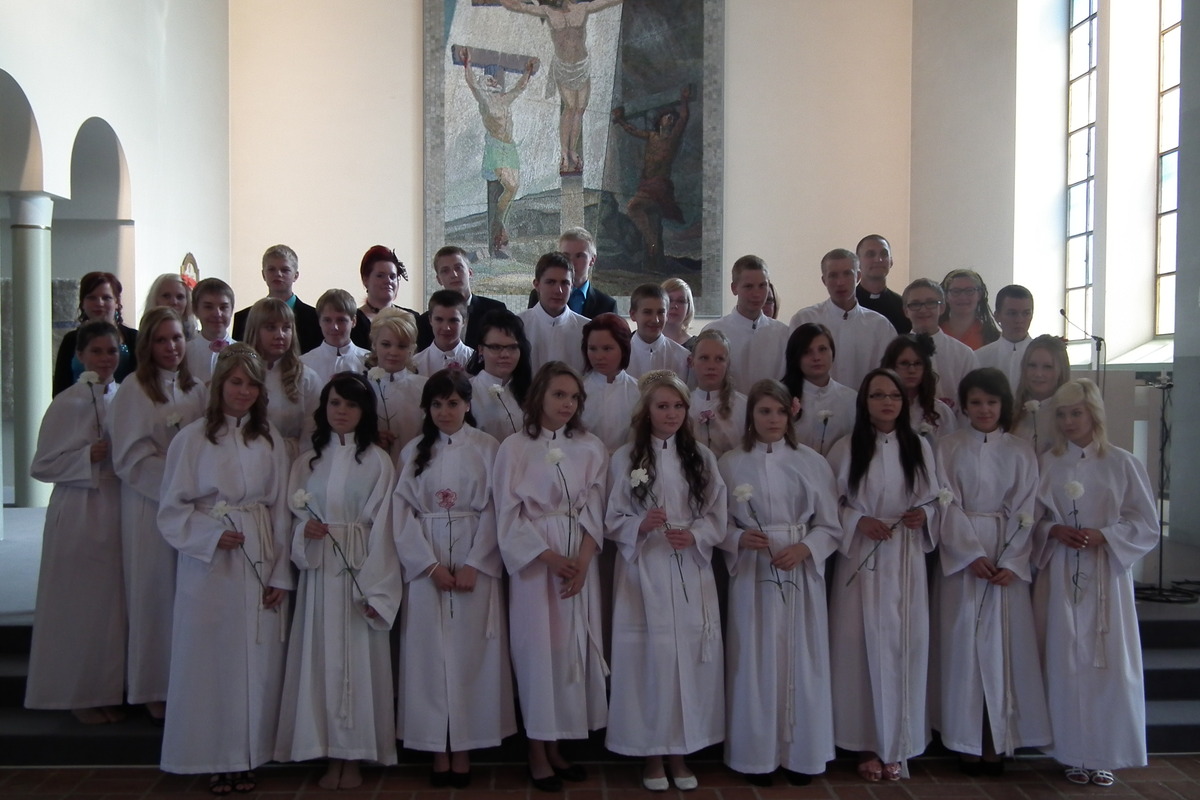 Rippikouluryhmä albat päällä kirkon etuosassa